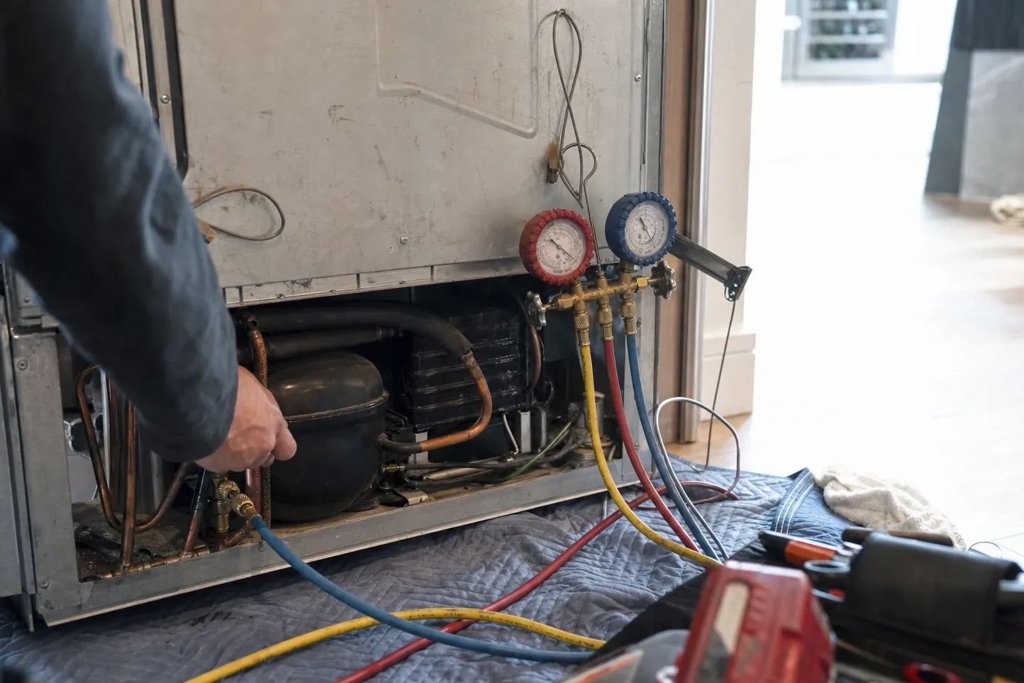 Manifold gauge set coupled to the compressor of a built-in refrigerator, an arm reaching in to the service valve